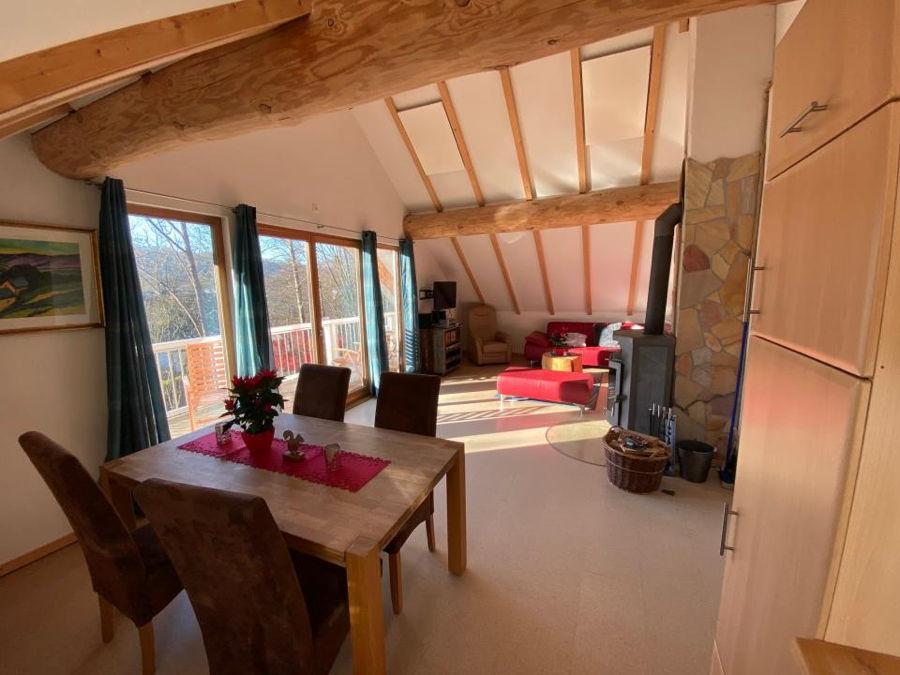 Wohnküche mit Esstisch, Kaminofen und rotem Sofa in der Dachgeschoß Ferienwohnung Eichhörnchen 2.