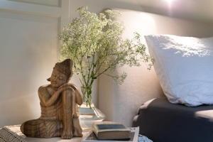 Eine Buddhafigur und ein Schafgarbenstrauß auf dem Nachttisch im Ferienhaus "Im Wald".