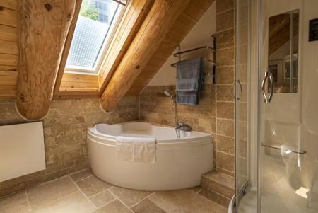 Ein großes Bad mit Dusche und großer Doppelbadewanne in einem Blockhaus des Ferienhausanbieters Eifelurlaub.
